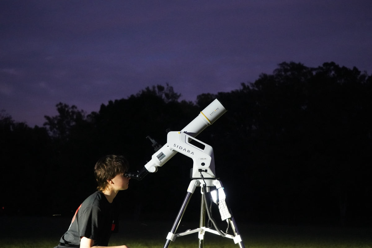 Boy looking through a Sidara telescope on its GoTo mount at night